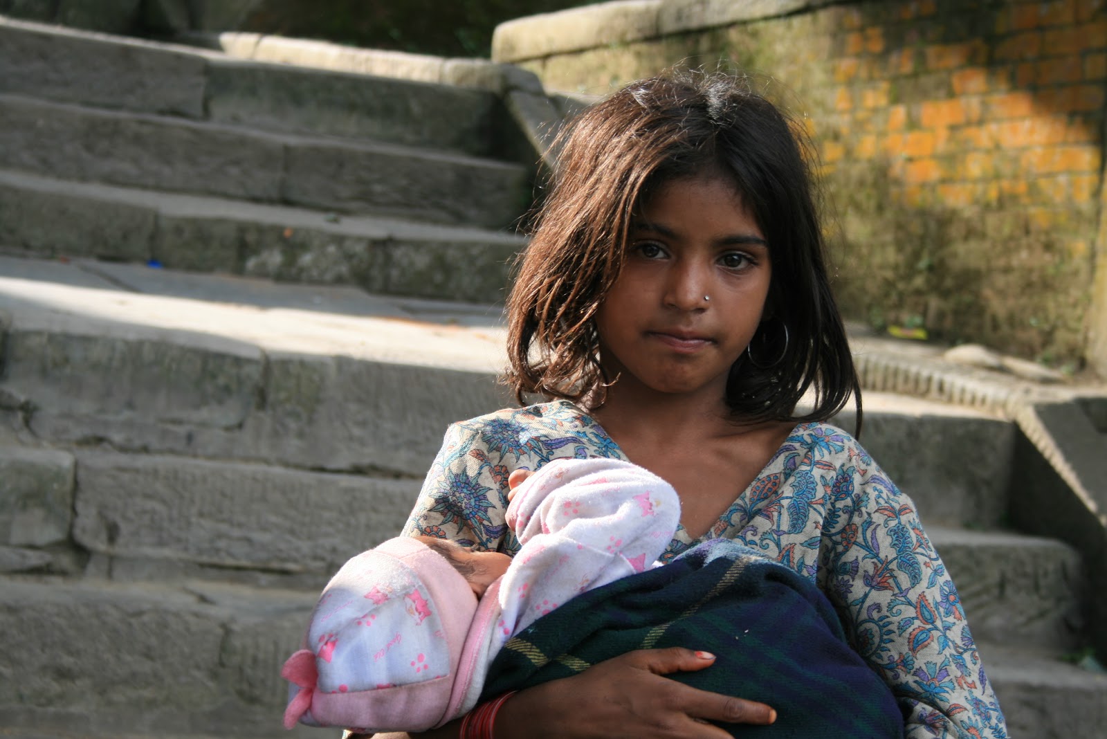 On the steps of the Swayambhu Temple, in Kathmandu, Nepal, a girl with a ba...